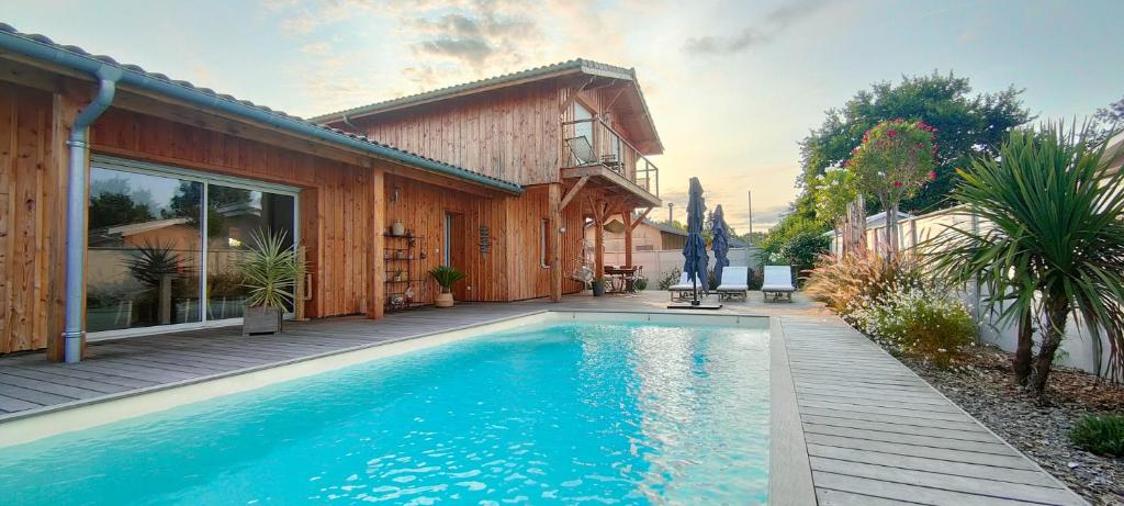 a swimming pool in front of a house at La Cabane Bohème, Maison d'hôtes Bassin d'Arcachon in Gujan-Mestras