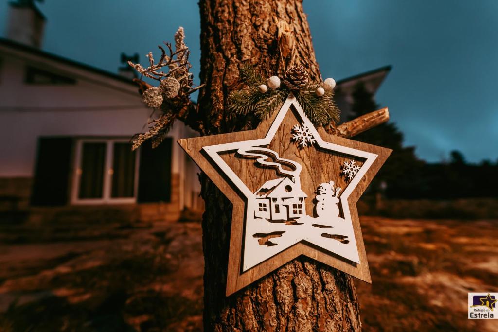 a gingerbread house sign on a tree at Refúgio na Estrela Penhas da Saúde in Penhas da Saúde