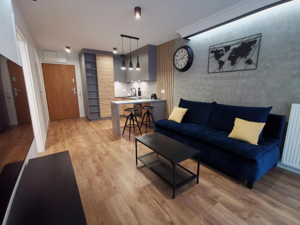 a living room with a blue couch and a kitchen at Apartament nad Odrą APARTMENT RIVER HOUSE in Szczecin