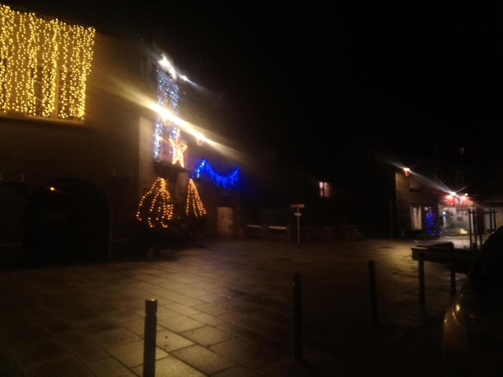 Una calle de noche con árboles de Navidad y luces en Bienvenue, en Saint-Pierre-de-Plesguen