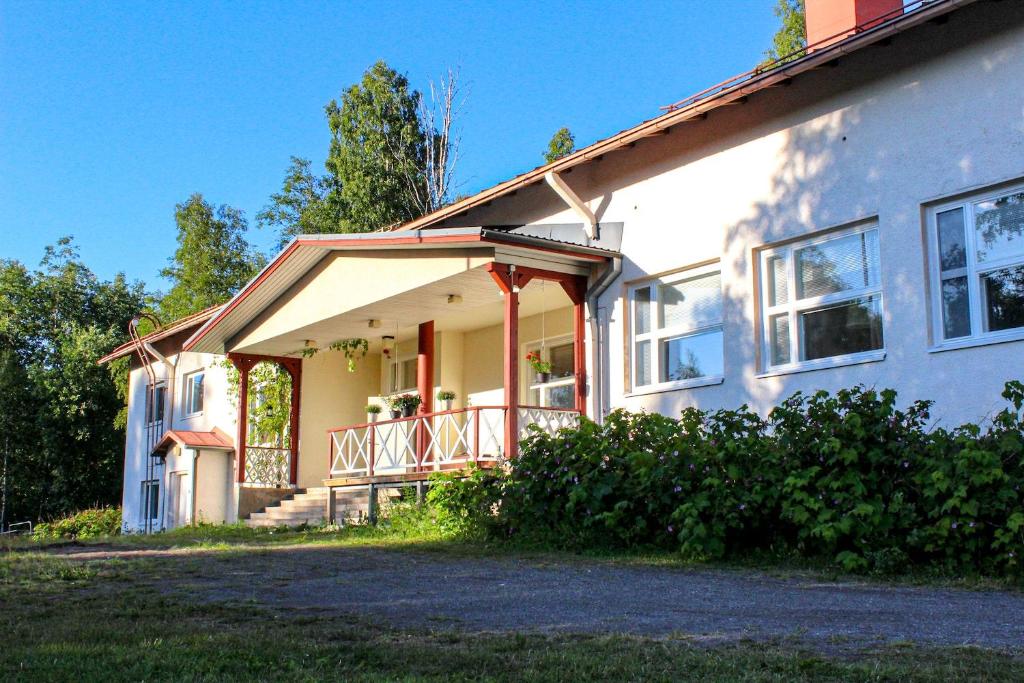 a white house with a porch and a person standing on the porch at Kotamäen Wanha Koulu in Pieksämäki