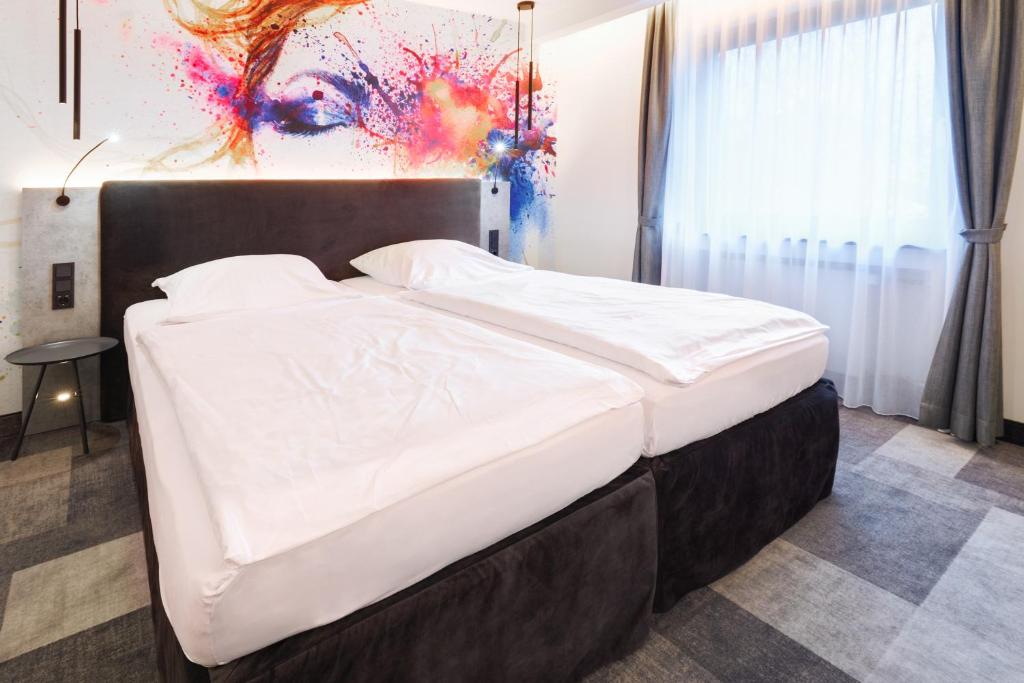 a bed in a bedroom with a painting on the wall at Hotel Stadt Grevenbroich mit Klimaanlage in Grevenbroich