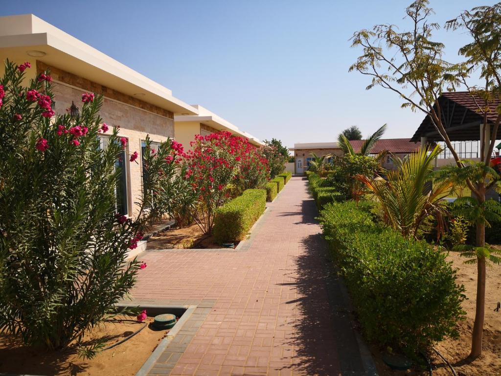 uma passarela de tijolos em frente a uma casa com flores cor-de-rosa em Almorouj Farm inn - Bidiya em Badīyah