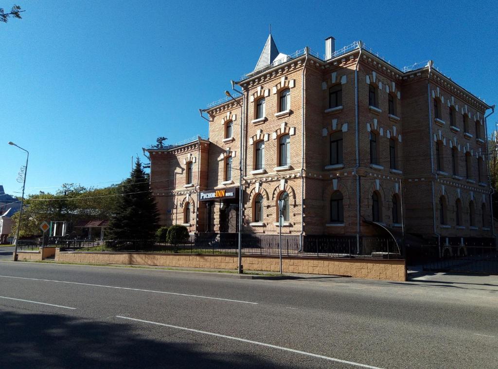een groot bakstenen gebouw aan de kant van een straat bij Отель «ПечорINN» Железноводск in Zjeleznovodsk