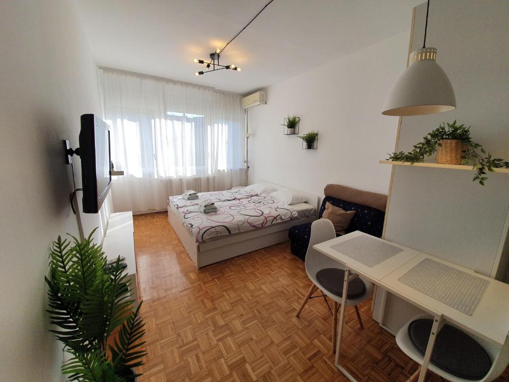 Habitación pequeña con cama, mesa y escritorio. en Oasis Belgrade, en Belgrado