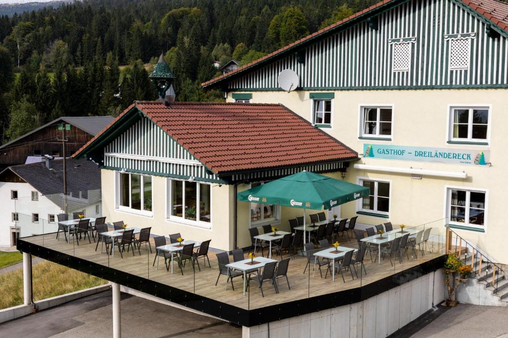a restaurant with tables and chairs on a deck at Gasthof Dreiländereck in Schwarzenberg am Bohmerwald
