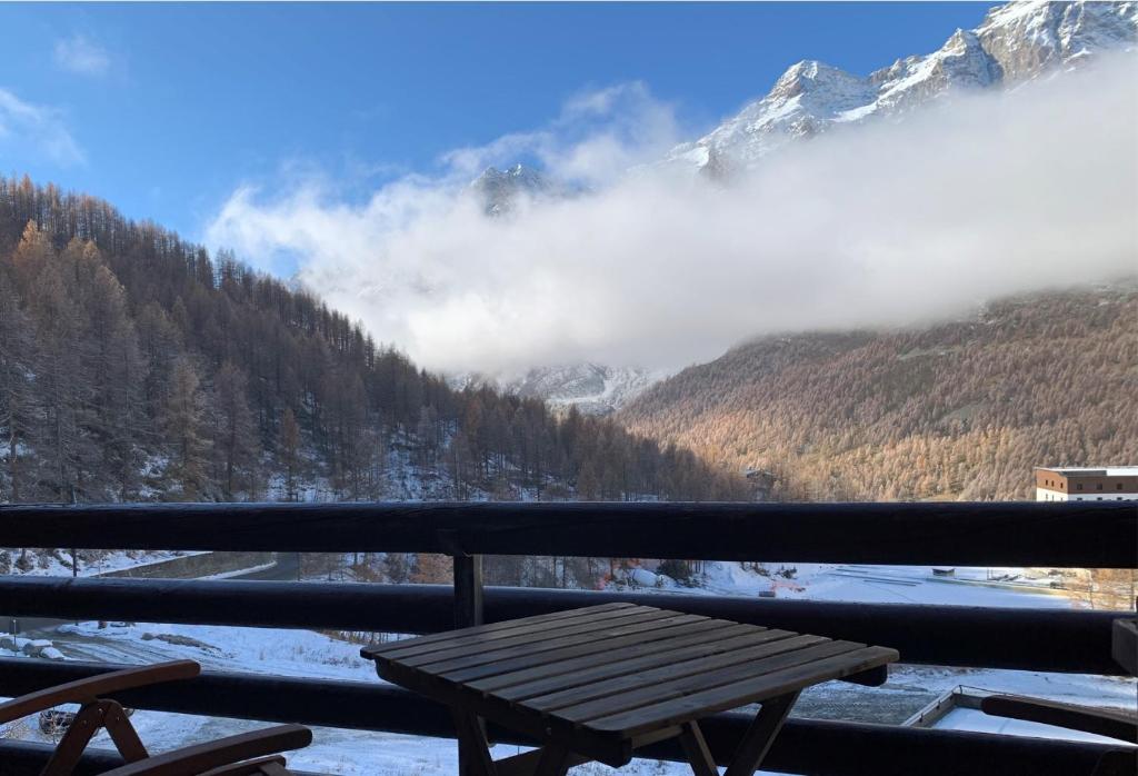 a wooden bench sitting on a balcony overlooking a snow covered mountain at Cervinia Apartment 2112 in Breuil-Cervinia