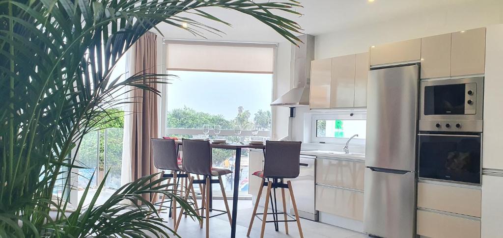 a kitchen with bar stools and a large window at HD Mogán Canal Apartments in Puerto de Mogán