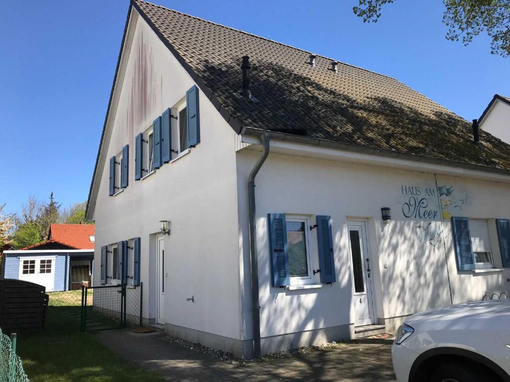 グロヴェにあるHaus am Meer Ferienhaus Insel Ruegの青いシャッターが付いた白い家
