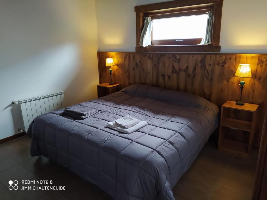 a bedroom with a bed with a window and two lamps at LodeJimmy in El Chalten