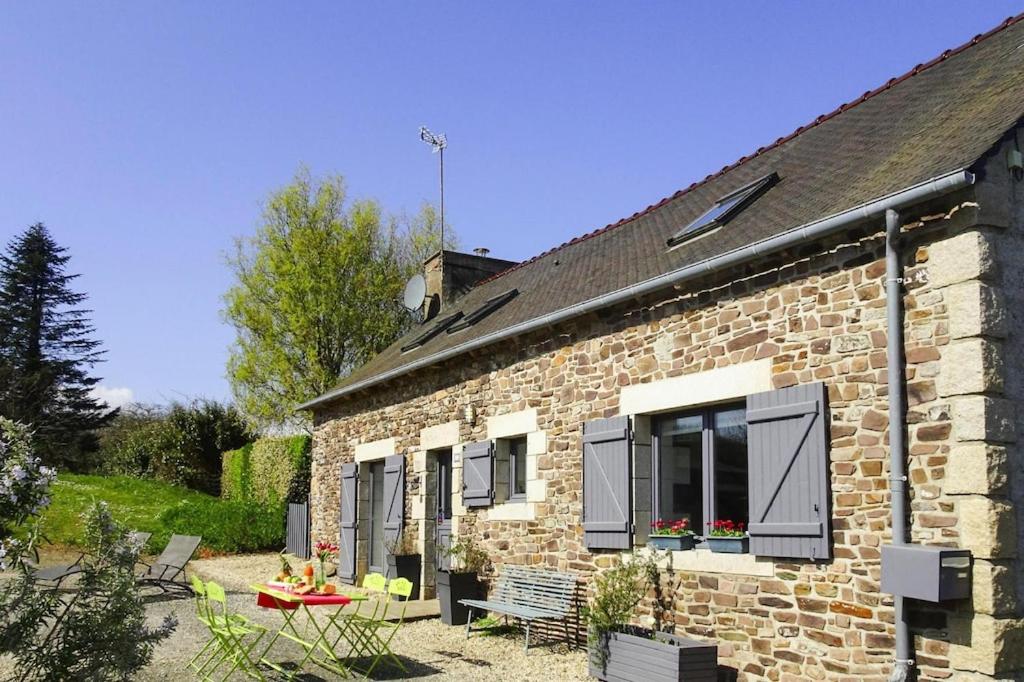 une maison en briques avec une table et des chaises devant elle dans l'établissement Stone House in Plouezec near Goelo Coast, à Plouézec