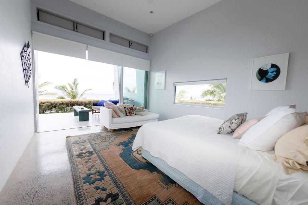 a white bedroom with a bed and a large window at Coast Cook Islands in Rarotonga