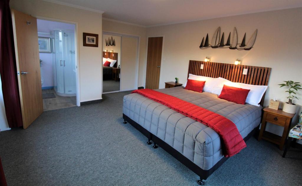 a bedroom with a large bed with red pillows at Labyrinth Gardens Guest House in Takaka
