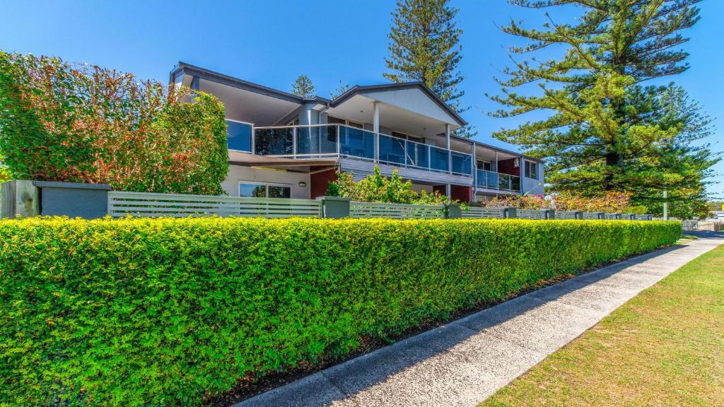 ein Haus mit einer Hecke davor in der Unterkunft Adrift Apartments in Yamba