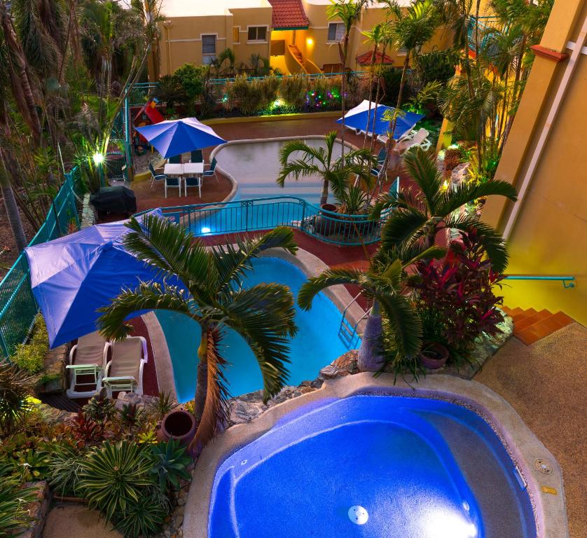 an overhead view of a swimming pool with palm trees and umbrellas at Toscana Village Resort in Airlie Beach