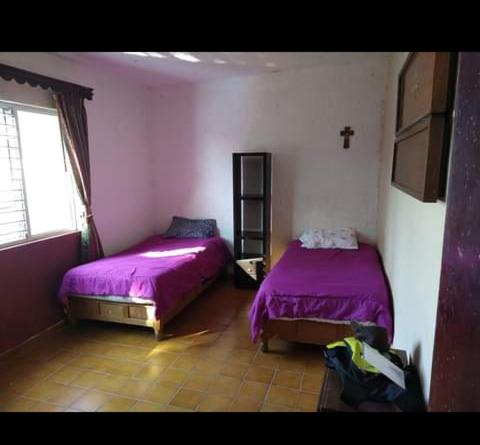 two beds in a room with purple sheets and a window at casa comoda sonora in Ciudad Obregón
