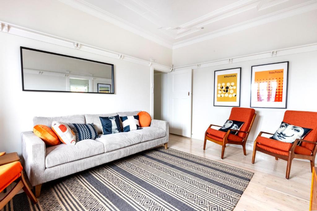 een woonkamer met een bank en twee stoelen bij Chic Bondi Beach Pad in Sydney