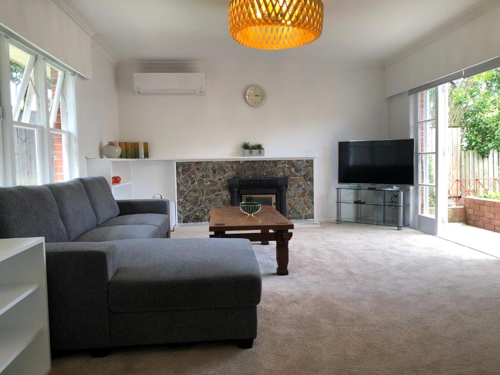 a living room with a couch and a fireplace at Comfortable Holiday Home at Mt Wellington in Auckland