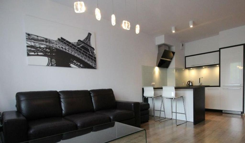 a living room with a black couch and a kitchen at Apartament ''Cleopatra 2'' z garazem, faktury VAT in Kielce