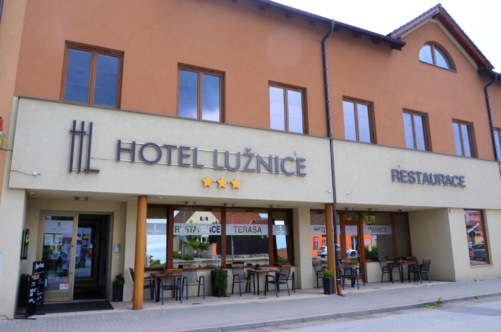 uma aldeia hoteleira com mesas e cadeiras em frente a um edifício em Hotel Lužnice em Planá nad Lužnicí