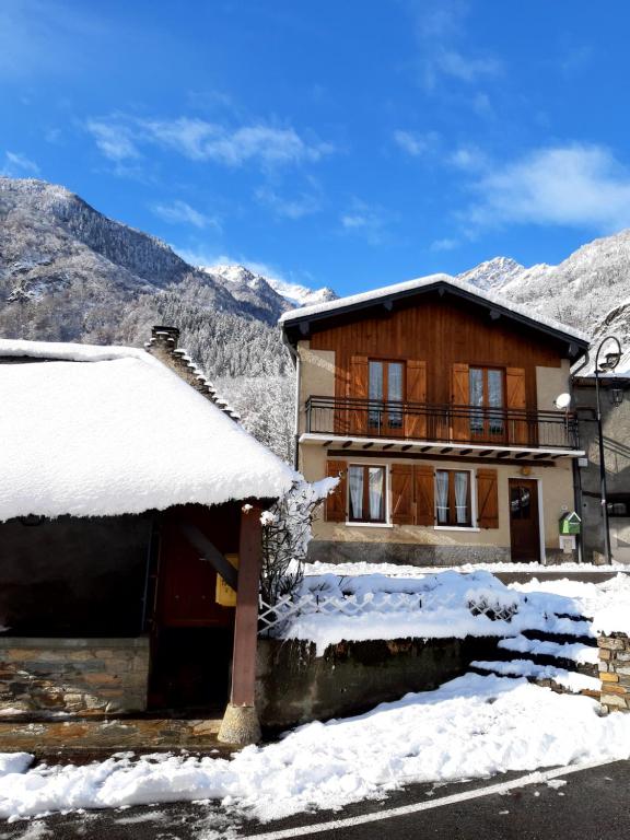 una casa de madera con nieve en el techo en Maison des trois ormeaux, en Cier-de-Luchon