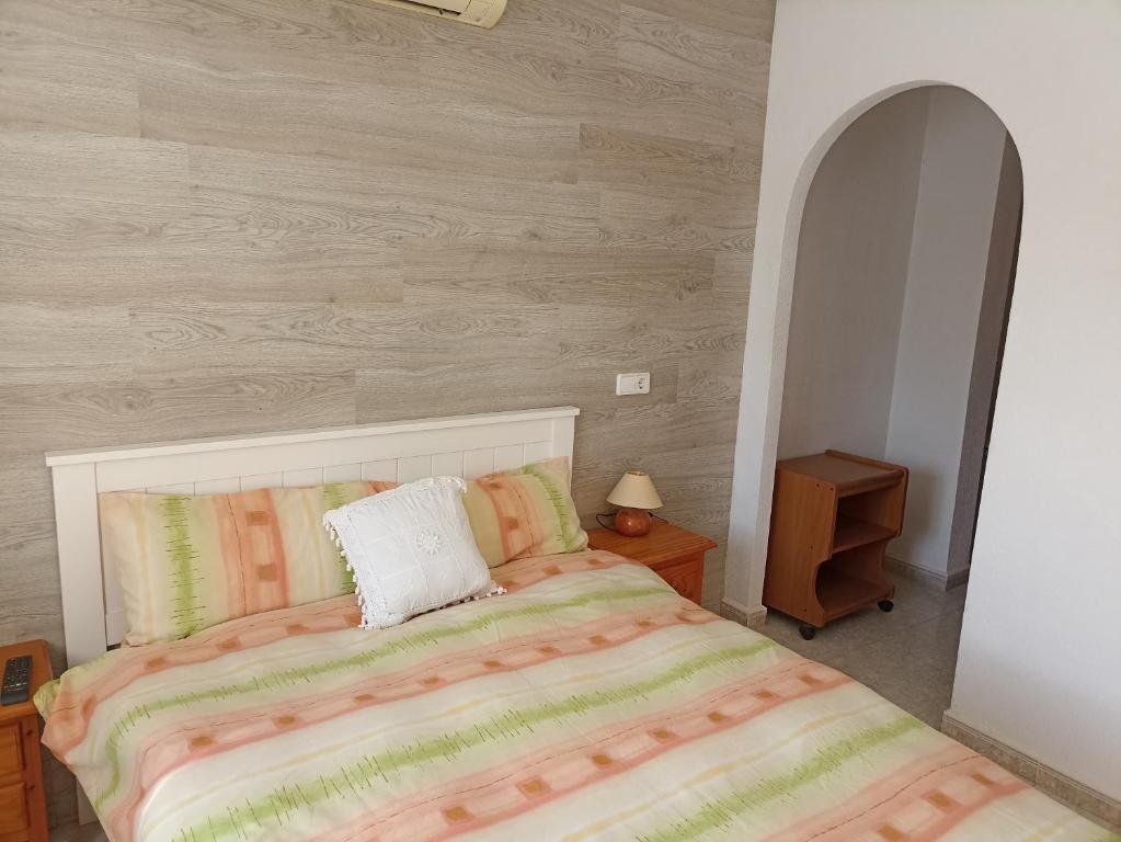 1 dormitorio con 1 cama y pared de madera en L'Apostille, en Mazarrón