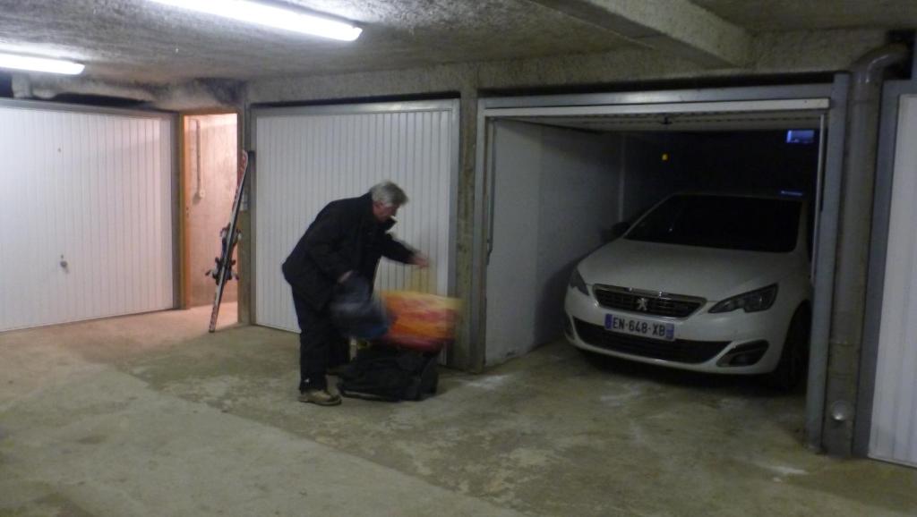 a man standing in a garage next to a car at Le Lièvre Blanc, appartement N°2 in Les Contamines-Montjoie