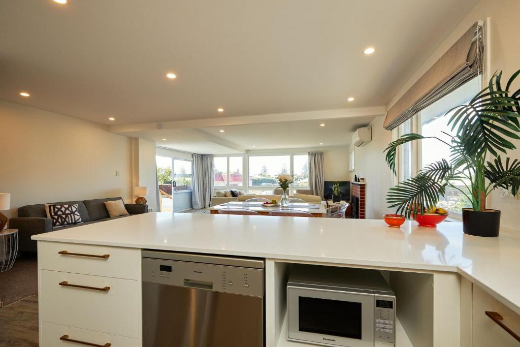 a kitchen with a white counter top and a living room at Koa Retreat in Kaikoura
