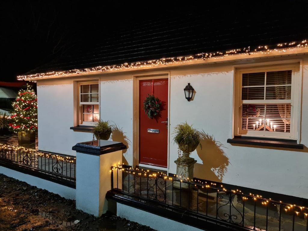 a house with a christmas tree and a red door at Kiltoy Cottage, Cosy 2 bedroomed Gate Lodge Cottage in Letterkenny