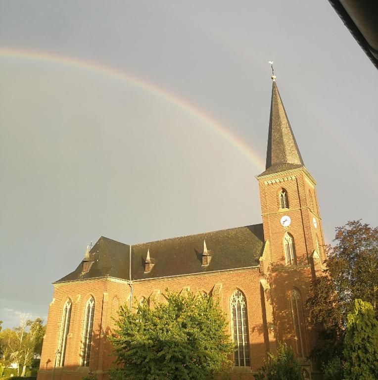 um arco-íris sobre uma igreja com uma torre de relógio em Ferienwohnung Pont an der Niers em Geldern