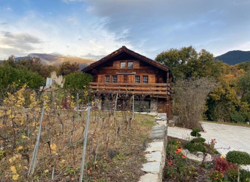 a wooden house with a fence in front of it at chalet à diolly in Savièse