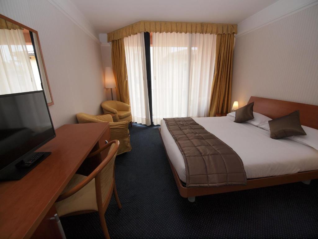 a hotel room with a bed and a desk and a television at Hotel San Rocco in Muggia
