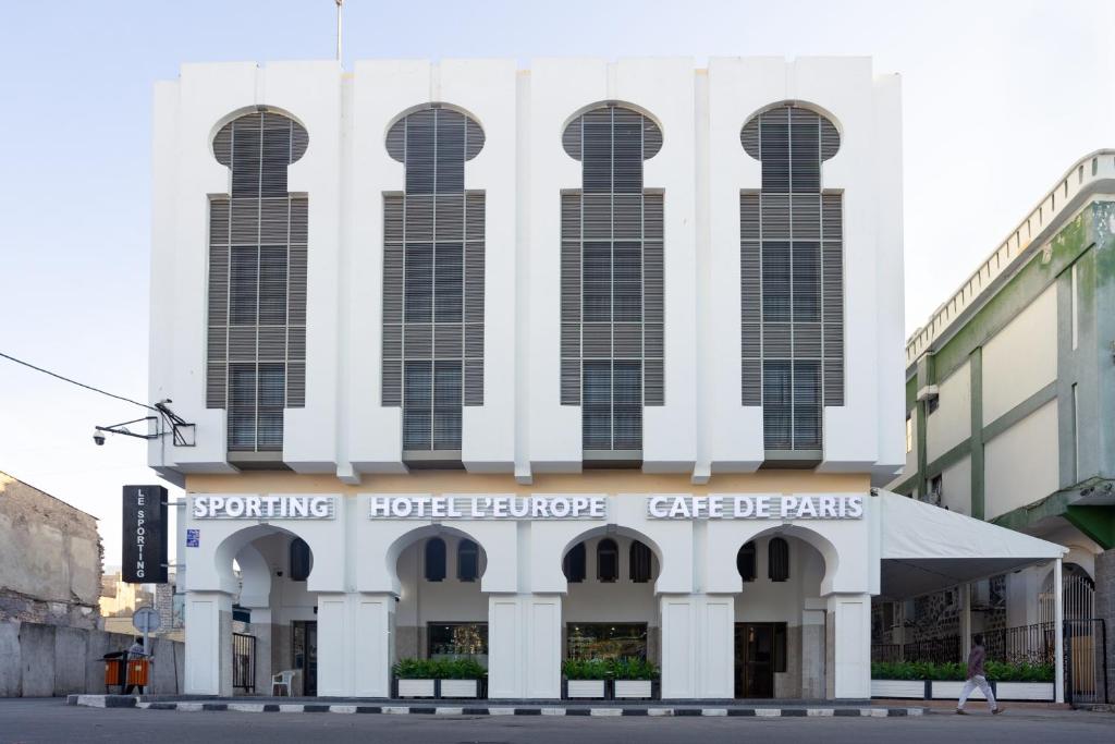 ein großes weißes Gebäude mit hohen Fenstern auf einer Straße in der Unterkunft Hôtel l'Europe in Dschibuti