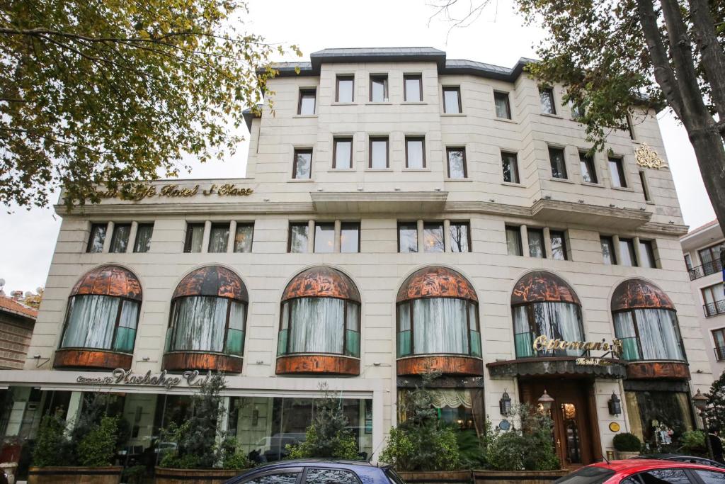 Un bâtiment blanc avec des fenêtres et des voitures garées devant. dans l'établissement Ottoman's Life Hotel S Class, à Istanbul