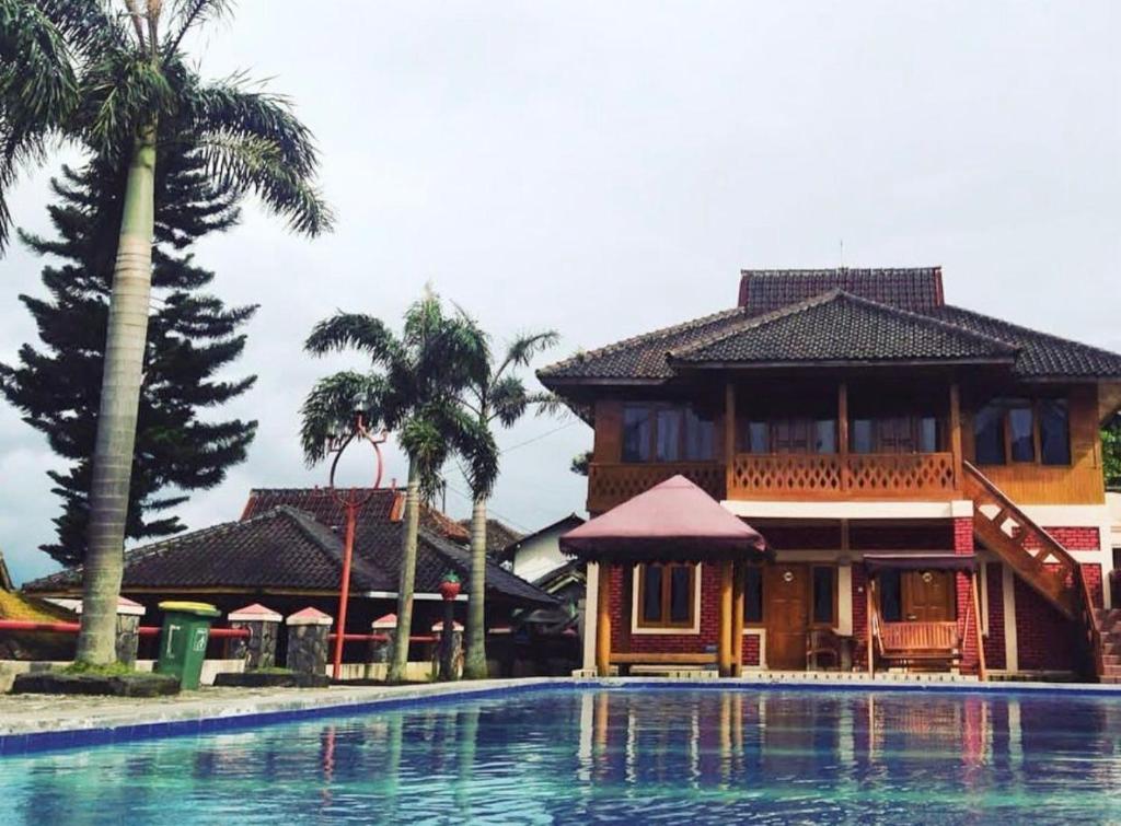 a house with a swimming pool in front of a building at Bungalow kampoengstrawberry ciwidey in Ciwidey