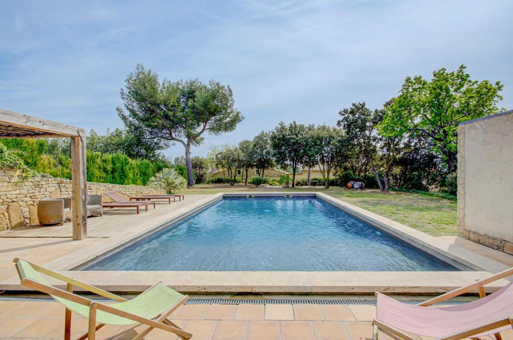 a swimming pool with two chairs and a table at Le Bercail de Montmirail in Sarrians