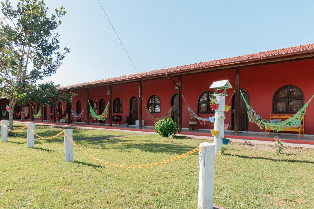 普拉亞做羅莎的住宿－Pousada Elementais do Rosa，前面的红色建筑,配有吊床