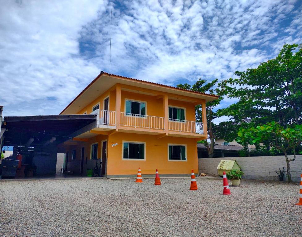 une maison jaune avec des cônes orange devant elle dans l'établissement Gênesis Beach Hostel! Quartos compartilhados e privativos na Pinheira, à Palhoça