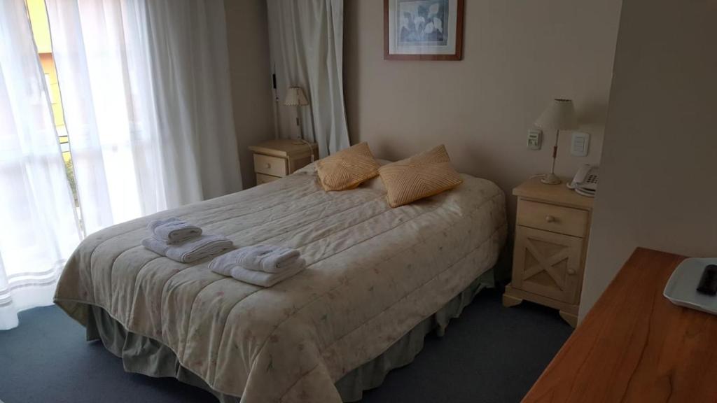 1 dormitorio con 1 cama con toallas en Hosteria Esturion Village en Villa Gesell