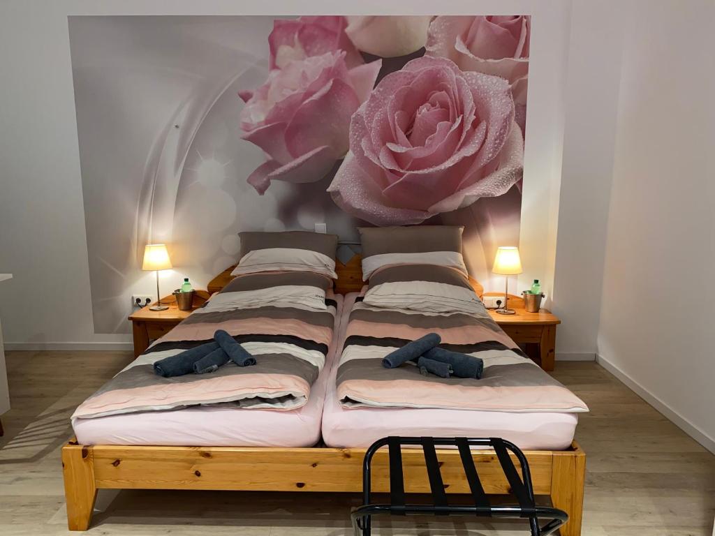 Home-Rose-Garden-Gästehaus kontaktloser Zugang في دوسلدورف: غرفة نوم مع أربعة أسرة مع الزهور الزهرية على الحائط