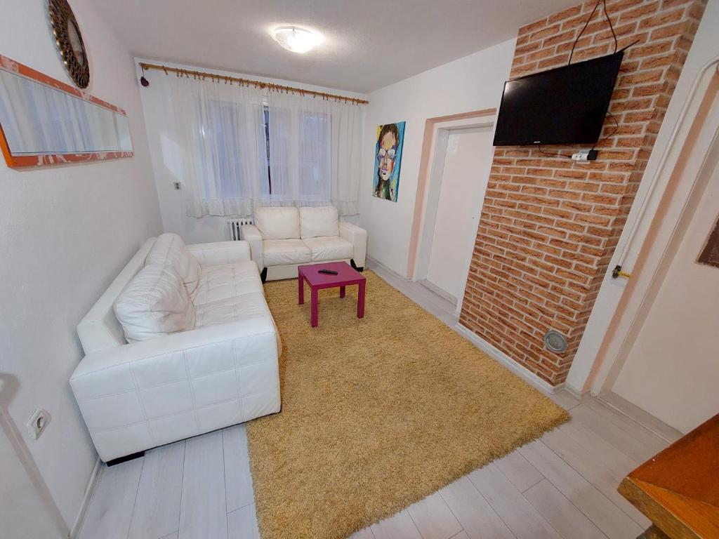 sala de estar con sofá blanco y pared de ladrillo en Apartments Bobito en Sarajevo