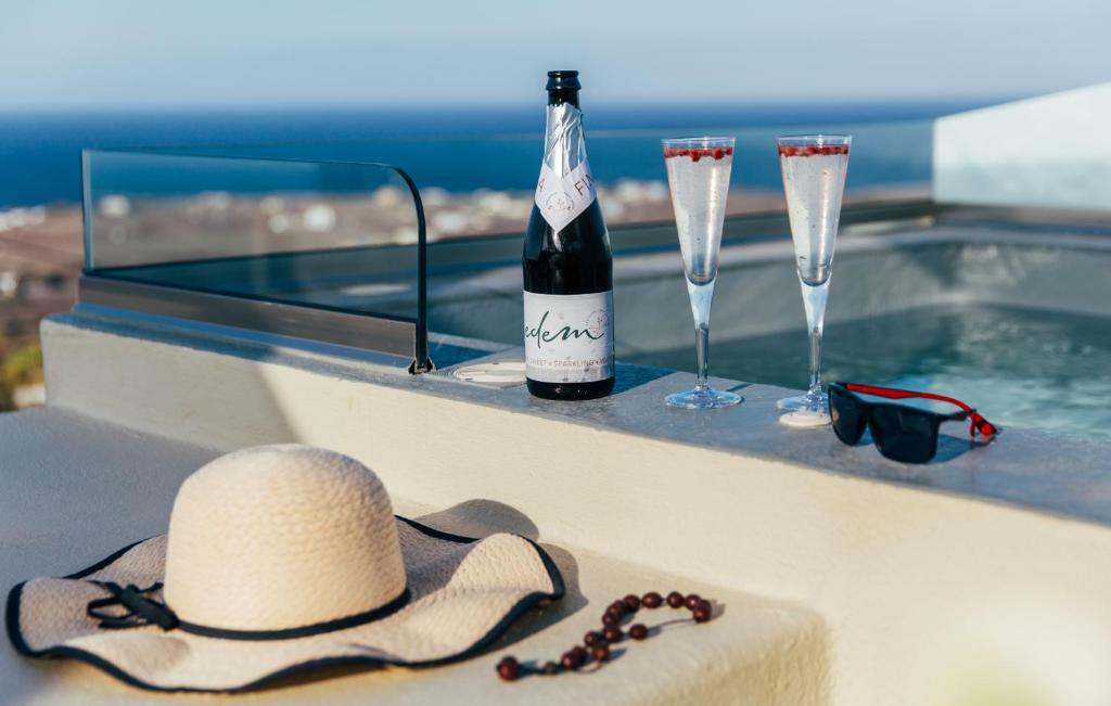 un cappello e dei bicchieri su un cornicione con una bottiglia di vino di Edem Luxury Hotel a Oia