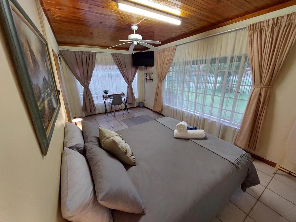 a bedroom with a large bed and a ceiling fan at Floret Cottage in Welkom