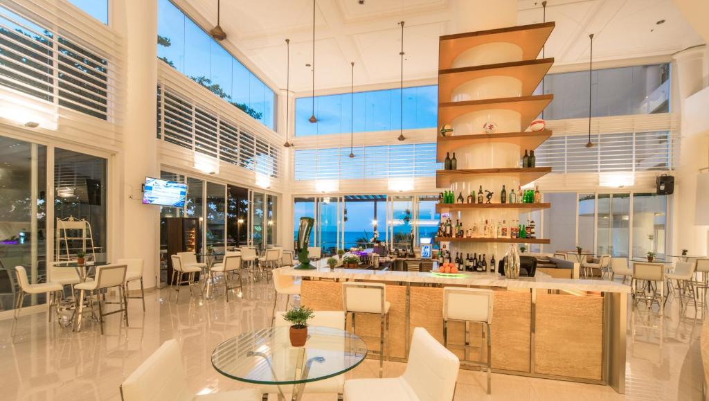 a restaurant with a bar with white chairs and tables at Flamingo Hotel by the Beach, Penang in George Town