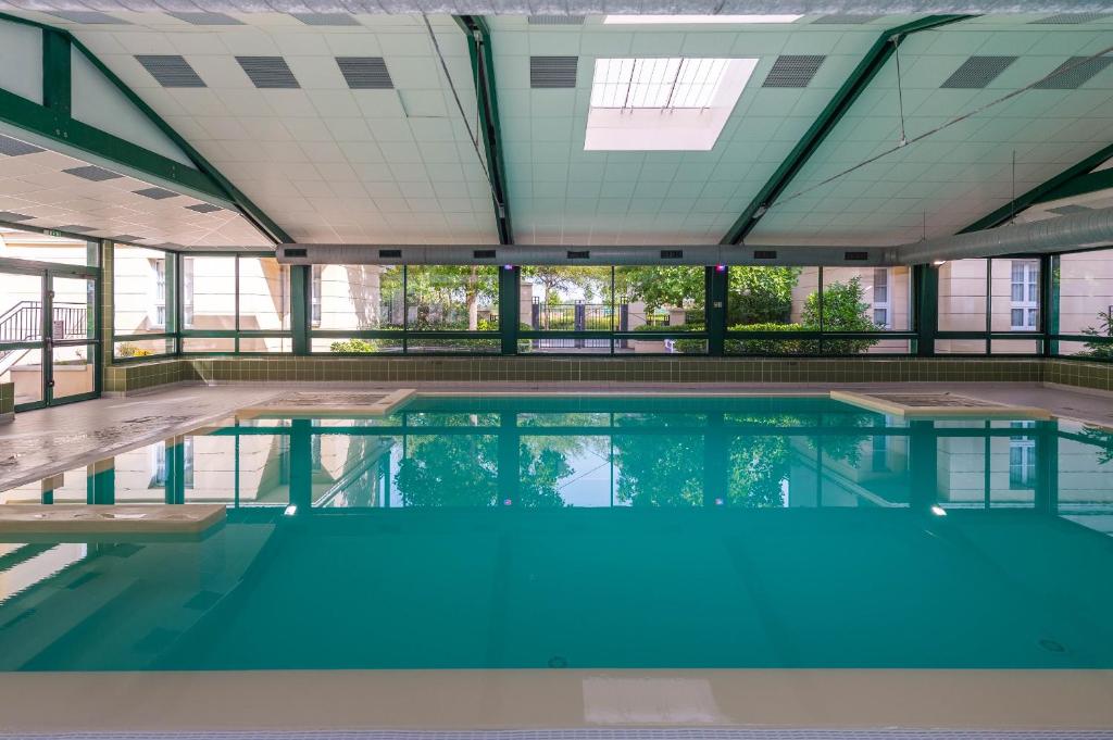 een groot zwembad met blauw water in een gebouw bij Appartements 4 à 5 personnes - Val d'Europe proche Disneyland in Serris