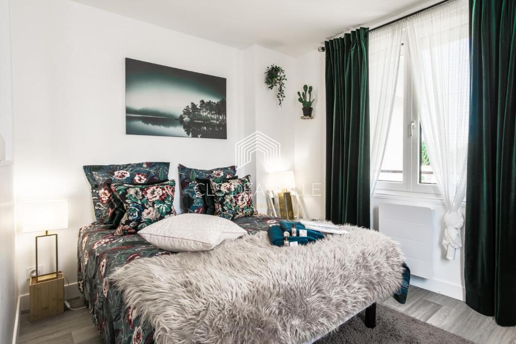 een slaapkamer met een bed met een deken en kussens bij La Deauvillaise CLS Deauville in Deauville