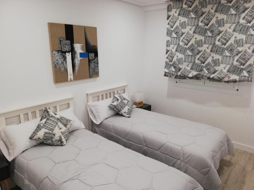 2 camas en una habitación con paredes blancas en Piso Ourense Centro, en Ourense