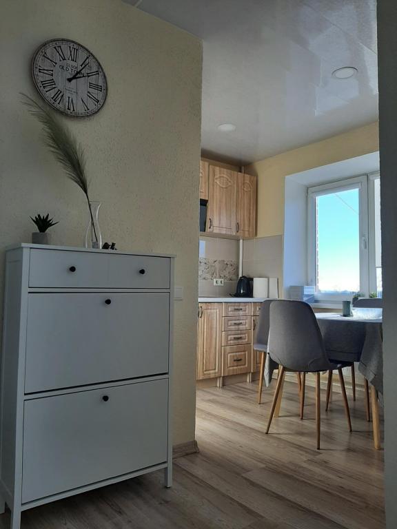 a kitchen and dining room with a clock on the wall at IR Apartment in Rēzekne