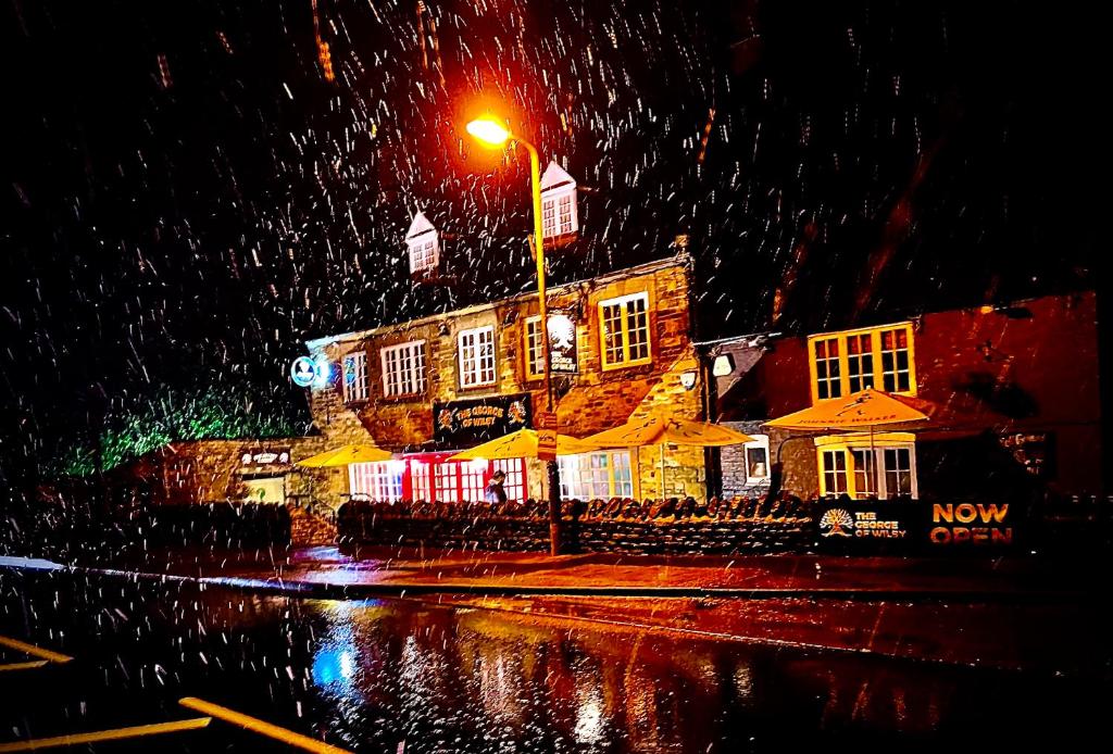 een gebouw met paraplu's in de regen 's nachts bij The Stables at The George Of Wilby in Wellingborough