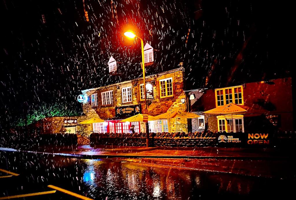 un edificio con sombrillas bajo la lluvia por la noche en The Stables at The George Of Wilby, en Wellingborough